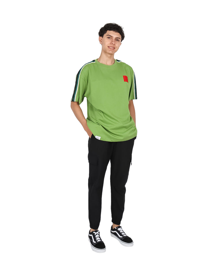 Hombre vistiendo playera color verde con franjas blancas y negras en las mangas y un pequeño detalle rojo al pecho.