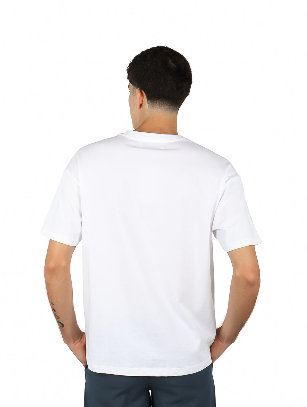 Hombre vistiendo playera blanca de manga corta con estampado gráfico en color verde en el pecho.