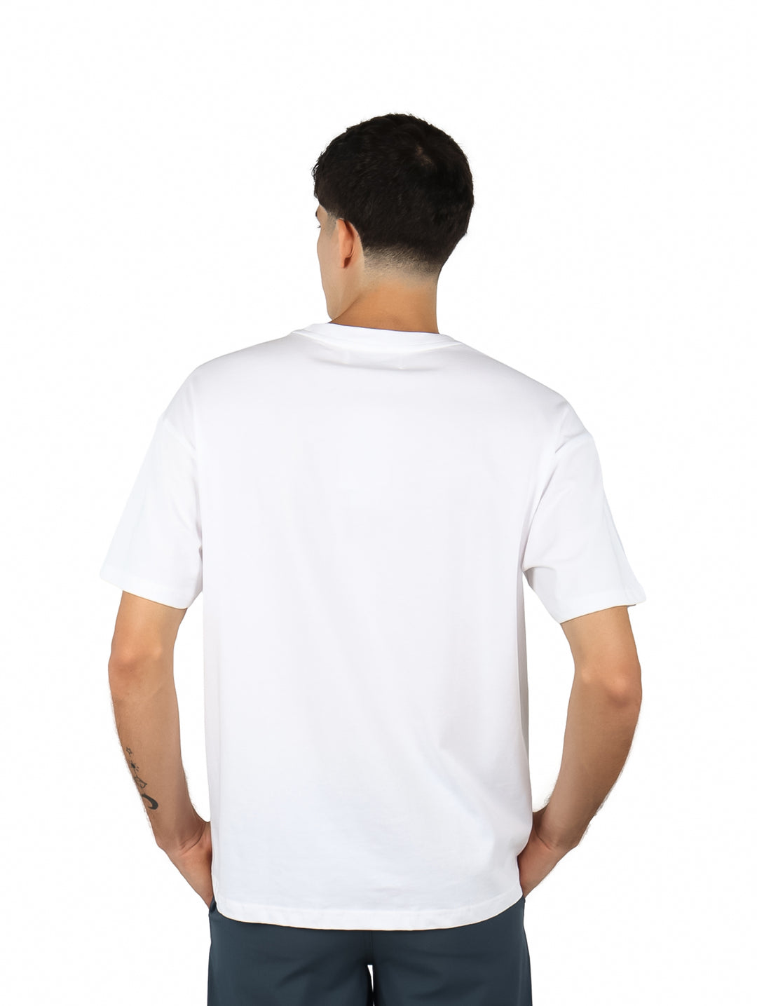 Hombre vistiendo playera blanca de manga corta con estampado gráfico en color verde en el pecho.