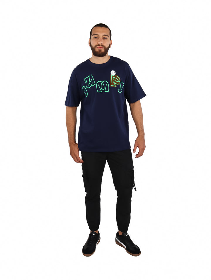Hombre vistiendo playera azul marino de manga corta con estampado gráfico en color verde lima en el pecho.