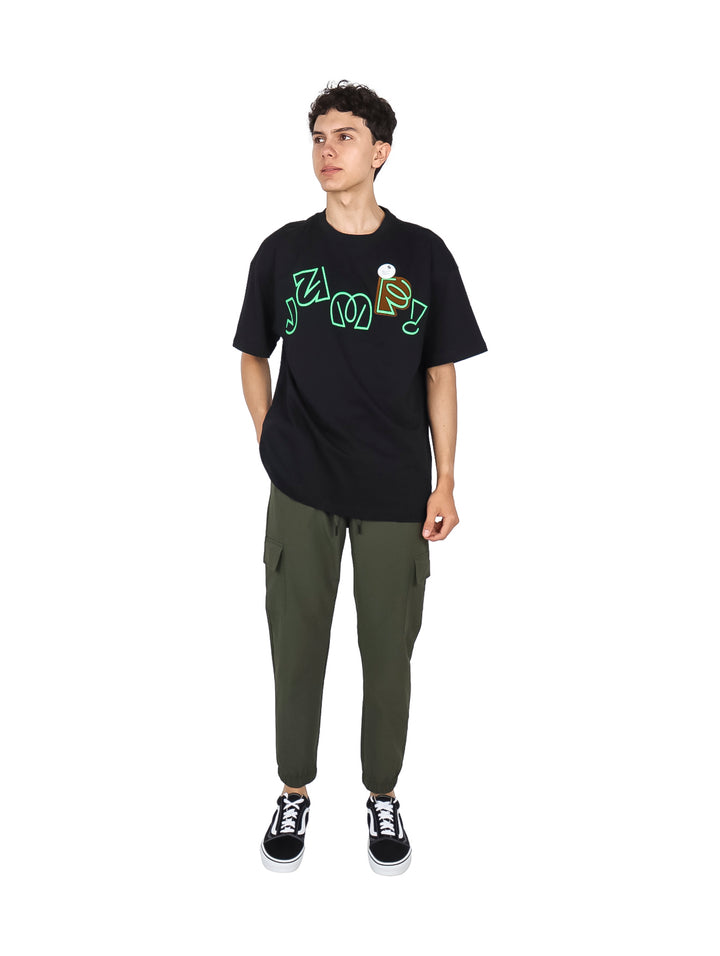 Hombre vistiendo playera negra de manga corta con estampado gráfico en color verde neón.