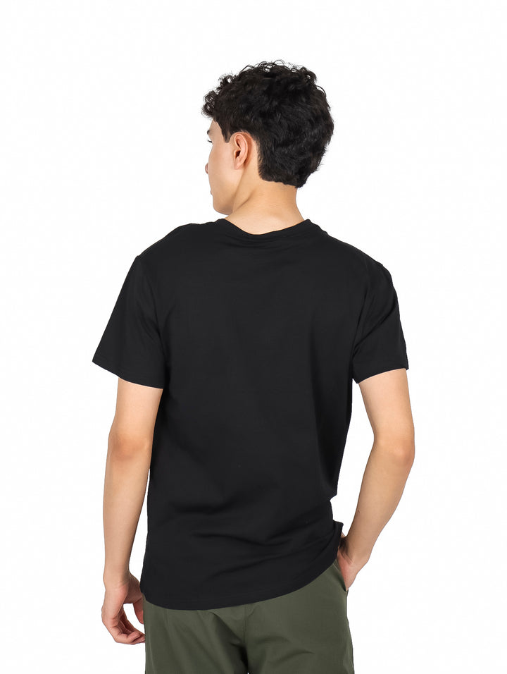 Hombre vistiendo una playera negra de manga corta con un pequeño estampado gráfico en el pecho.