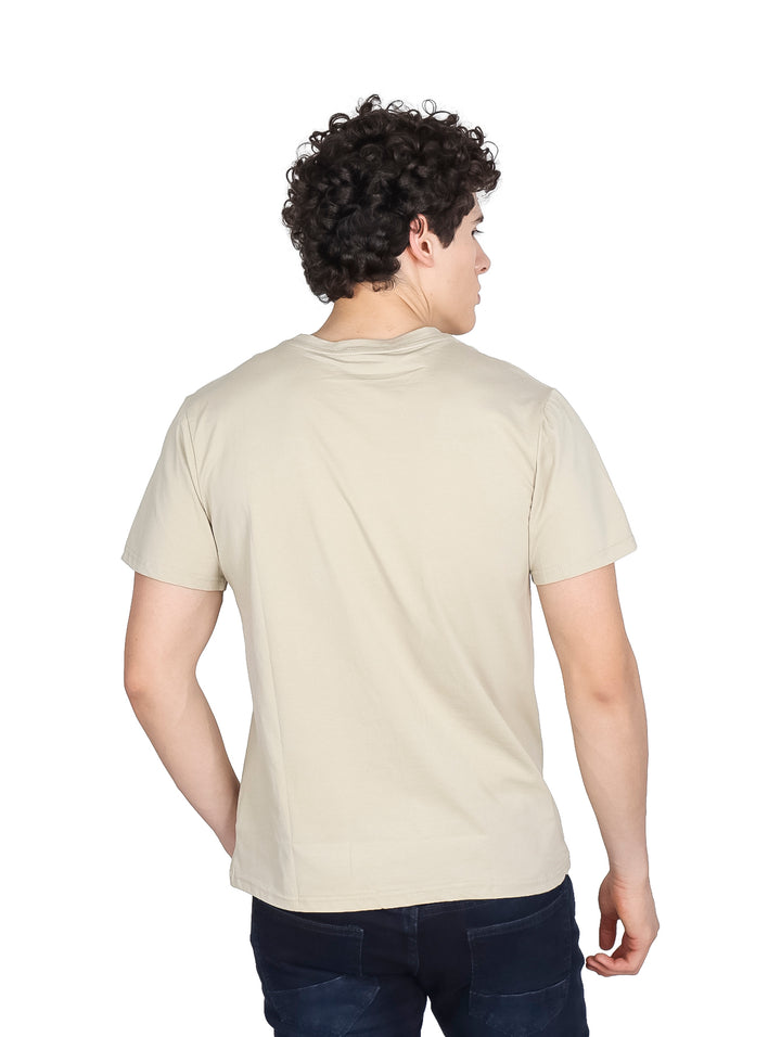 Hombre vistiendo una playera de manga corta color beige con un pequeño detalle gráfico en el pecho.
