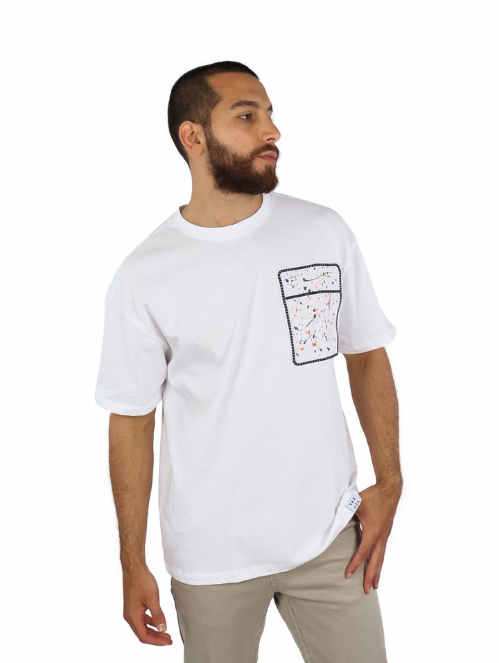 Hombre vistiendo playera blanca de manga corta con un detalle de bolsillo estampado multicolor en el pecho.