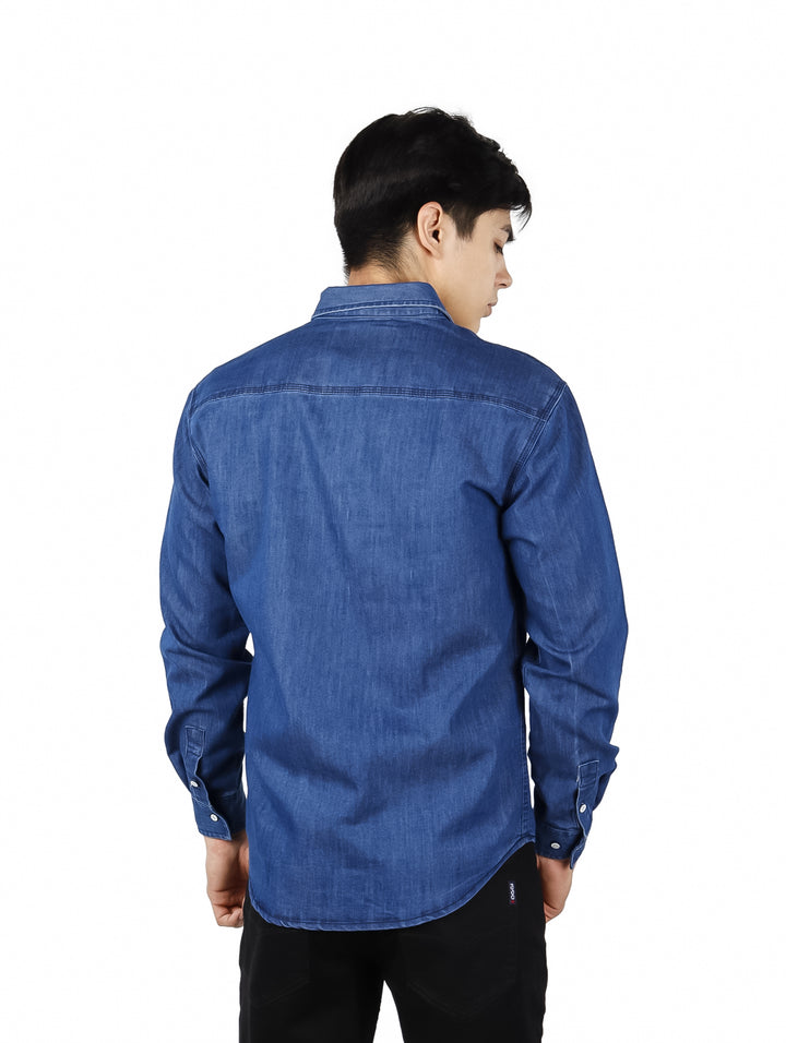 Hombre vistiendo una camisa azul de manga larga estilo denim con botones frontales.