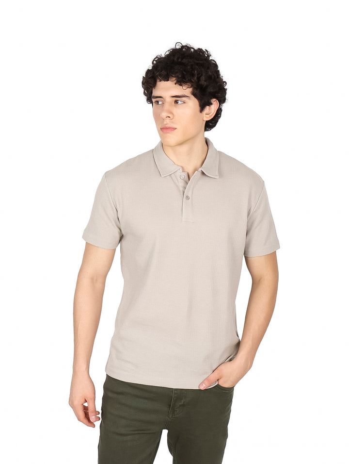 Hombre vistiendo una playera polo de color beige con cuello y manga corta.