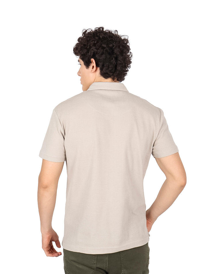 Hombre vistiendo una playera polo de color beige con cuello y manga corta.