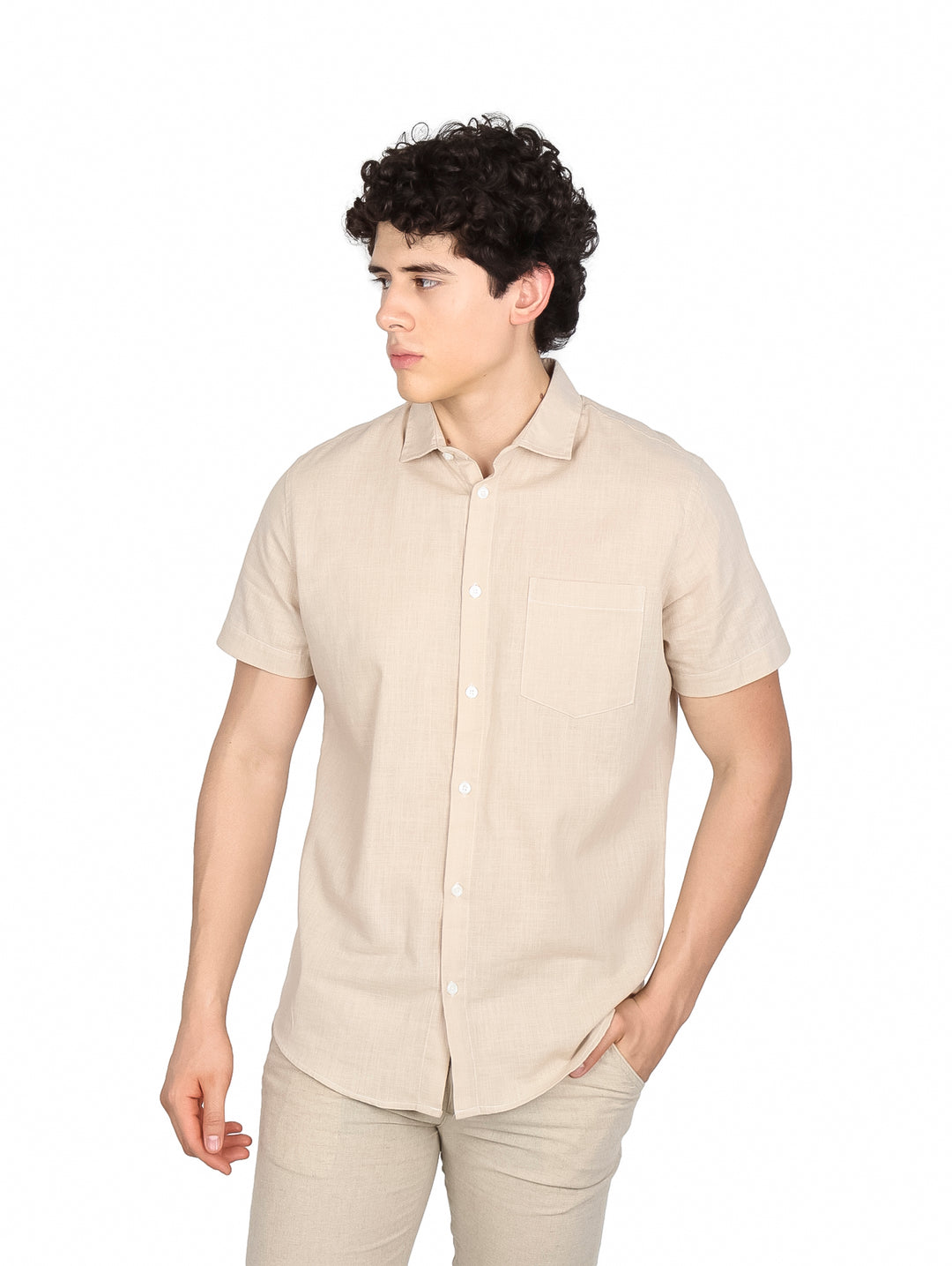 Hombre vistiendo camisa de manga corta color khaki con un bolsillo en el pecho y botones frontales.