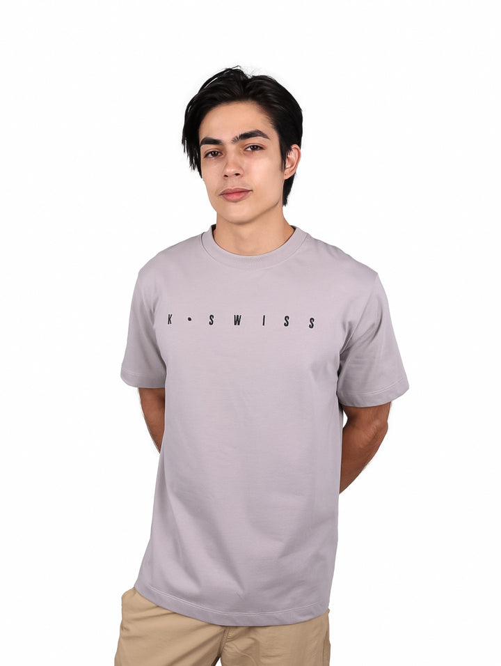 Hombre vistiendo una playera de manga corta color gris con el logo de K-Swiss en el pecho.