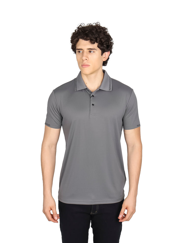 Hombre vistiendo una playera polo color gris oscuro con detalles decorativos en el cuello y mangas.