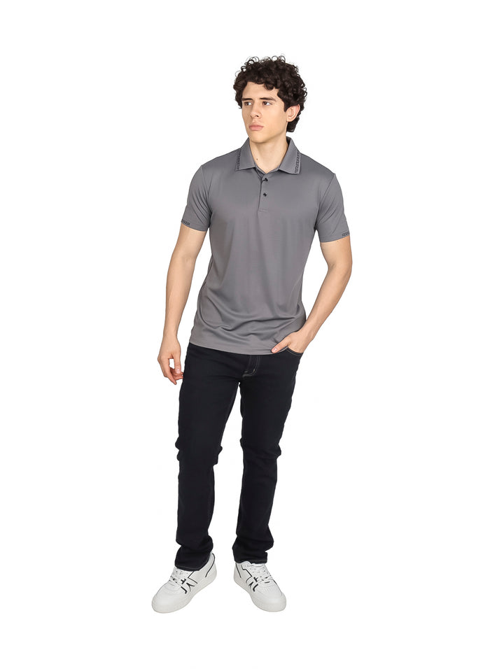 Hombre vistiendo una playera polo color gris oscuro con detalles decorativos en el cuello y mangas.