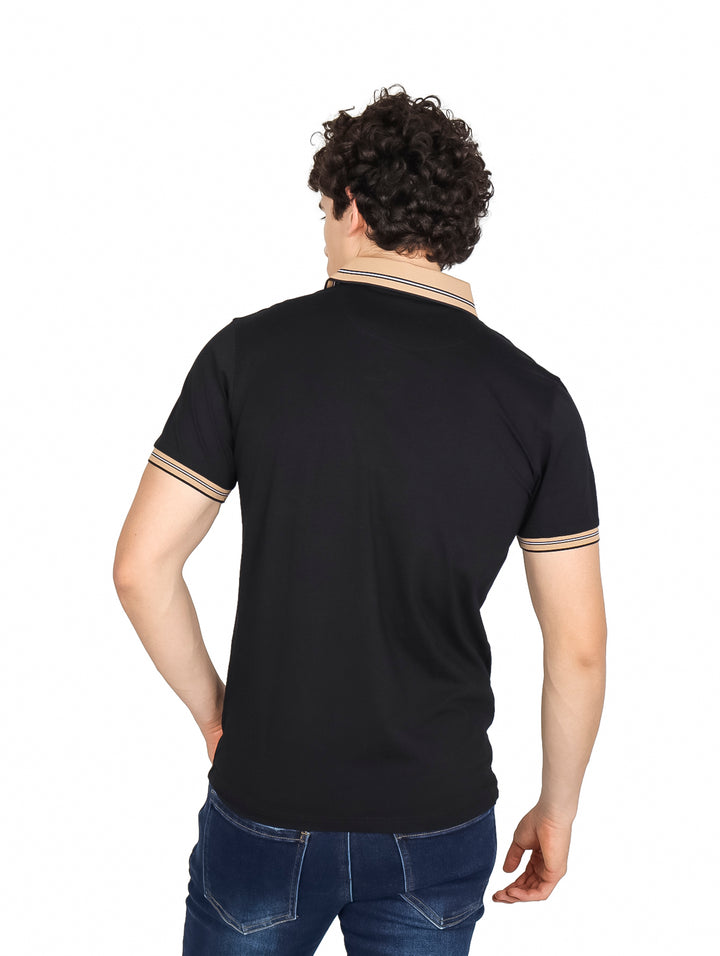 Hombre vistiendo playera polo color negro con detalles en beige en el cuello y puños de las mangas.