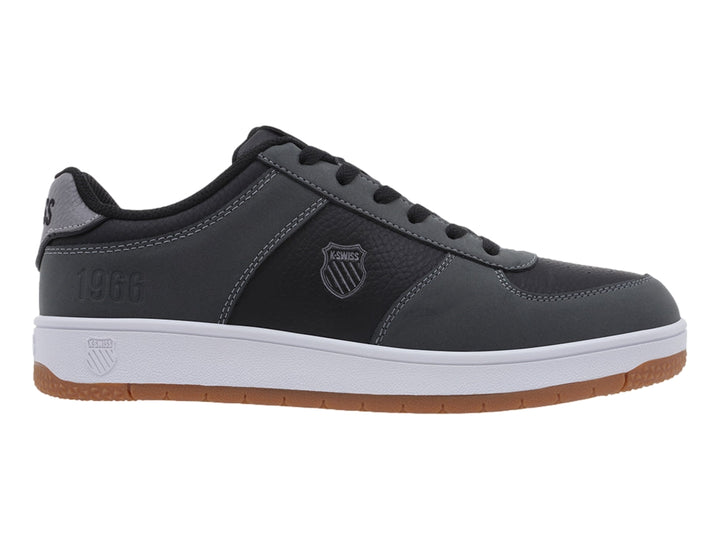 Tenis K-Swiss color gris oscuro con suela blanca y base de goma marrón, vista lateral.