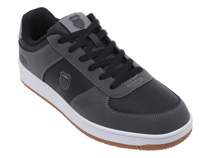 Tenis K-Swiss color gris oscuro con suela blanca y base de goma marrón, vista lateral.