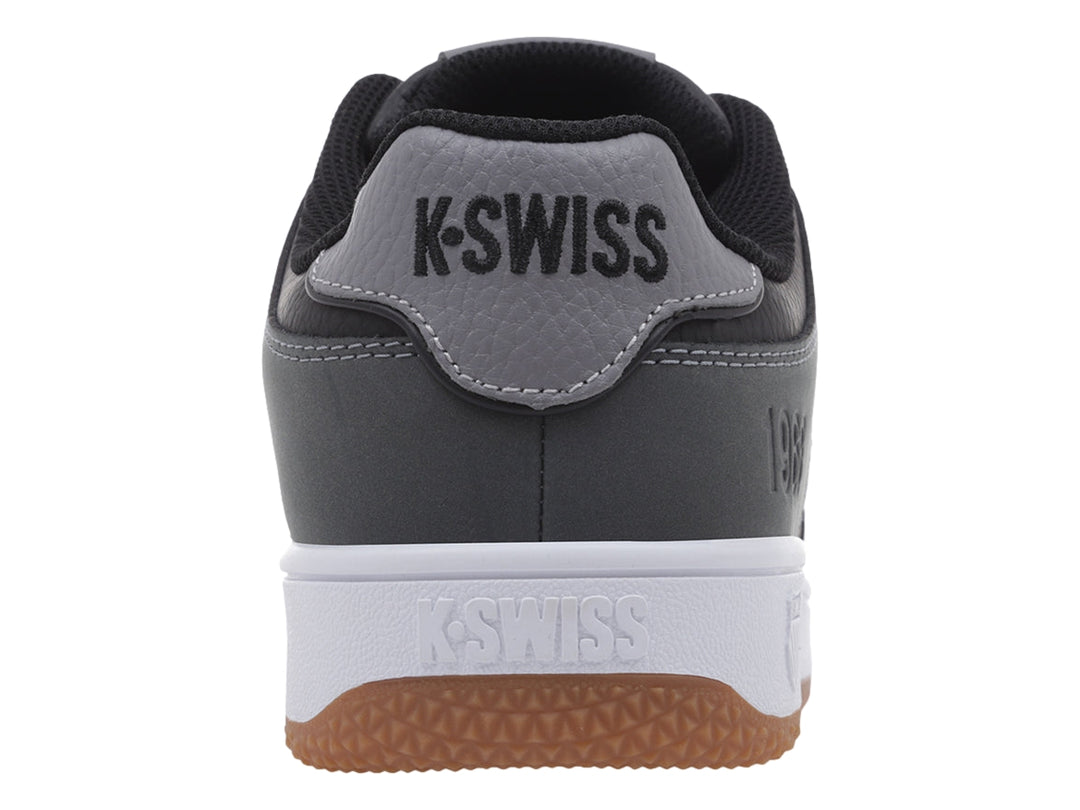 Tenis K-Swiss color gris oscuro con suela blanca y base de goma marrón, vista lateral.