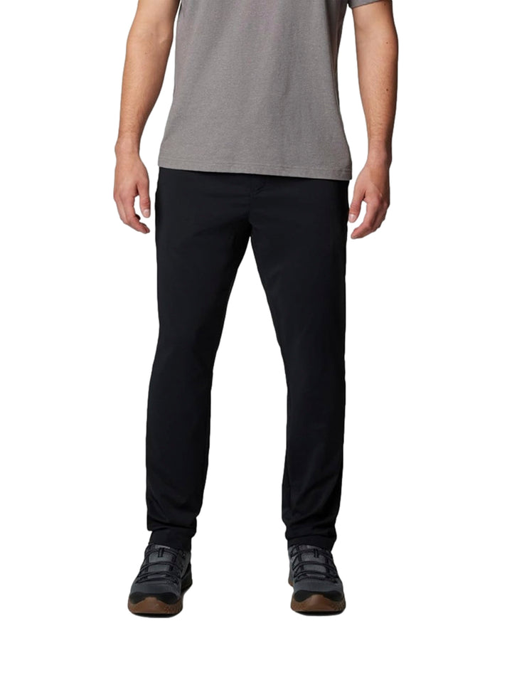 Hombre vistiendo pantalones tipo chino color negro de la marca Columbia con camiseta gris.