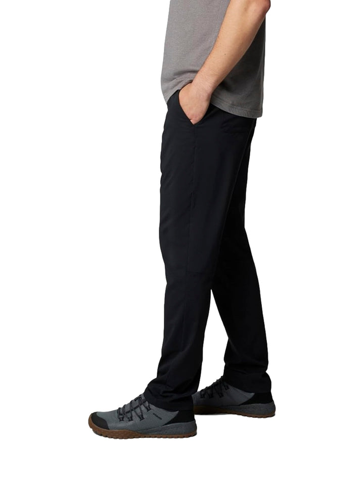 Hombre vistiendo pantalones tipo chino color negro de la marca Columbia con camiseta gris.