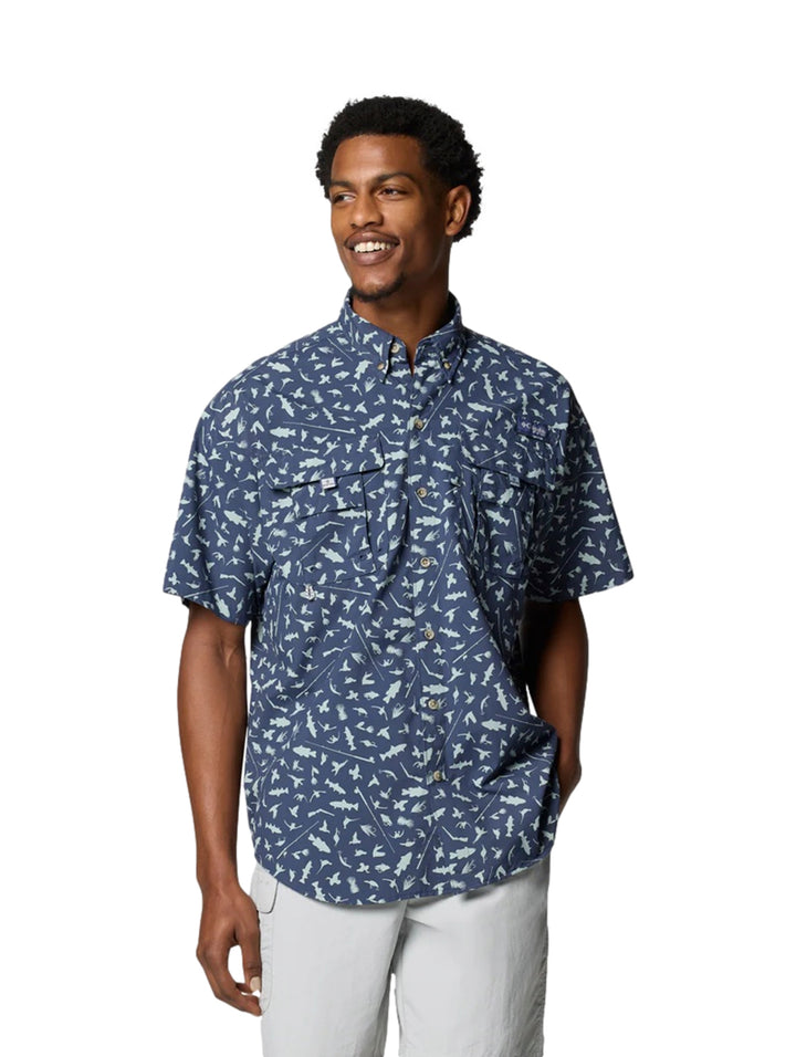 Hombre vistiendo camisa Columbia azul de manga corta con estampado de peces blancos.