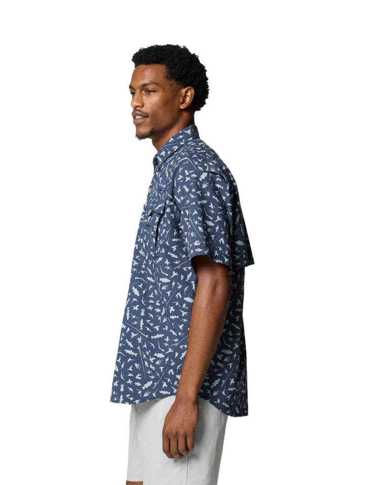 Hombre vistiendo camisa Columbia azul de manga corta con estampado de peces blancos.