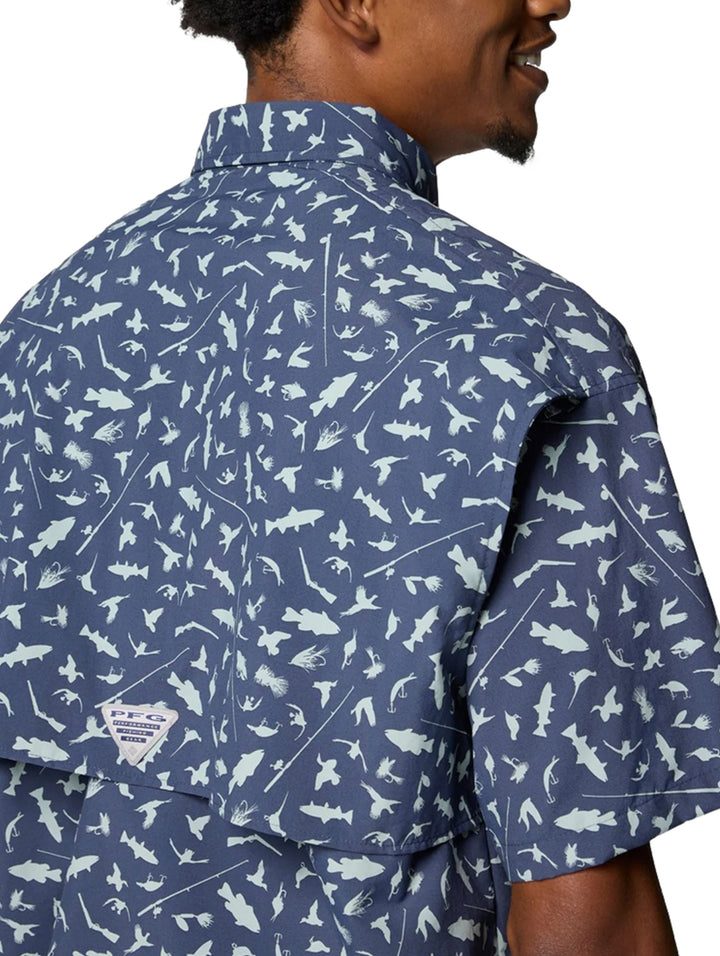 Hombre vistiendo camisa Columbia azul de manga corta con estampado de peces blancos.