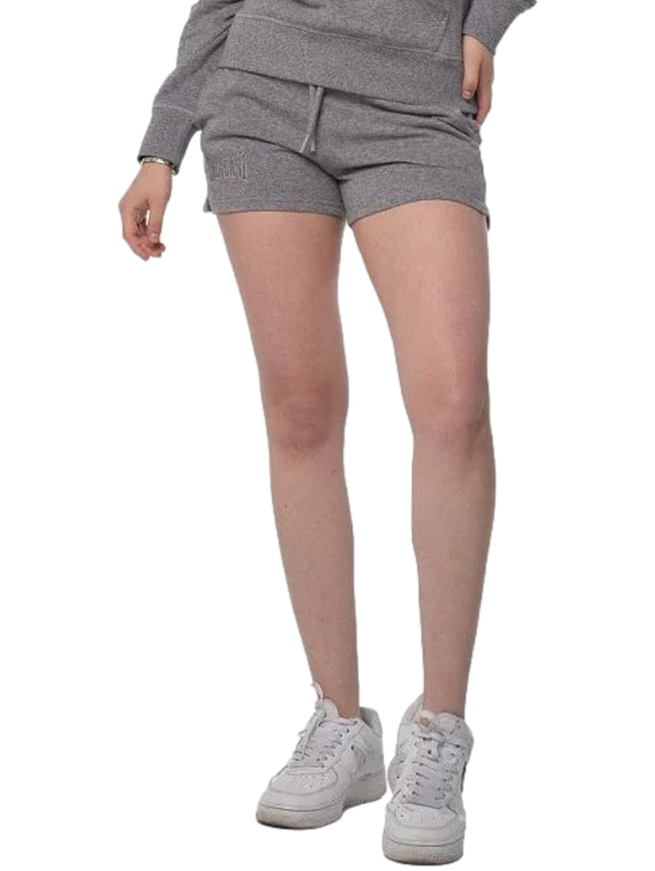 Mujer vistiendo shorts deportivos color gris de la marca Everlast y tenis blancos.