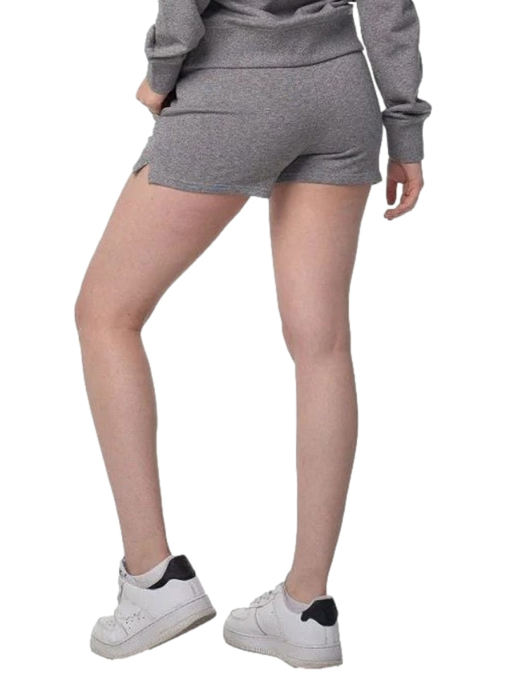 Mujer vistiendo shorts deportivos color gris de la marca Everlast y tenis blancos.