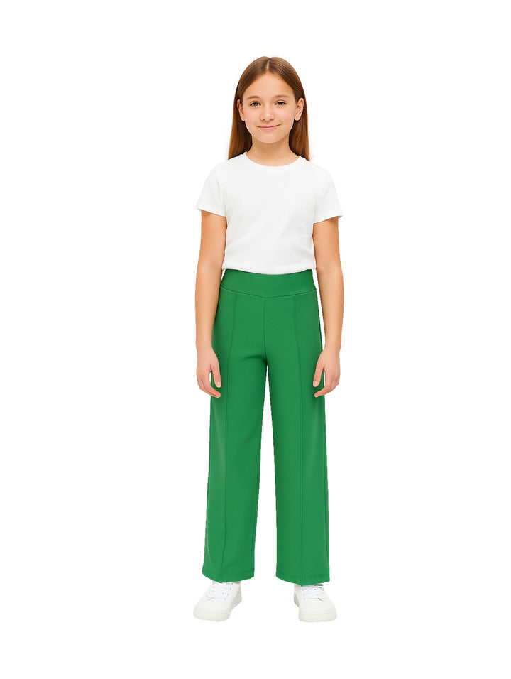Niña modelando un pantalón acampanado de color verde con una camiseta blanca.