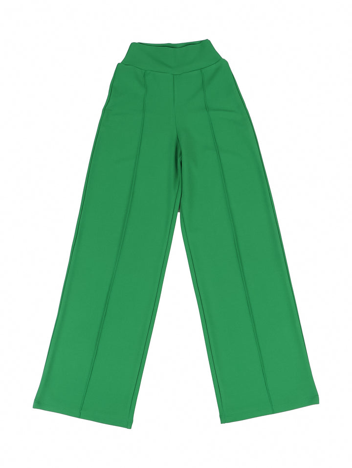 Niña modelando un pantalón acampanado de color verde con una camiseta blanca.