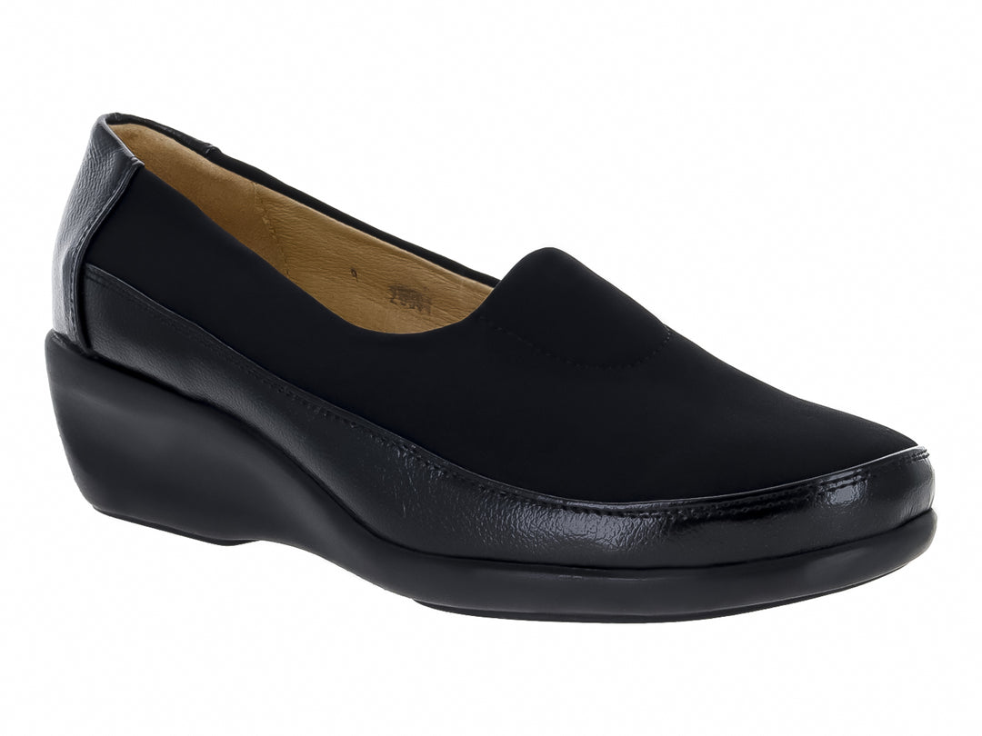 Zapato negro cerrado tipo slip-on con suela de cuña y materiales sintéticos y textiles.