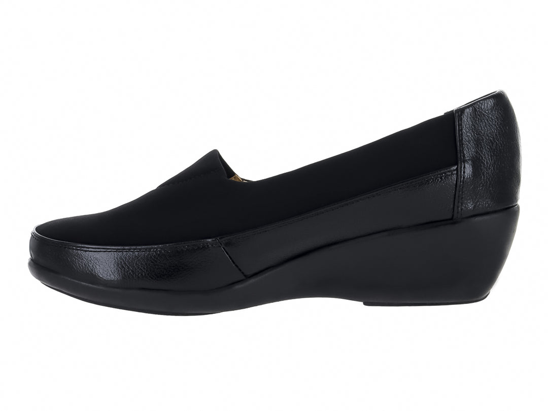 Zapato negro cerrado tipo slip-on con suela de cuña y materiales sintéticos y textiles.