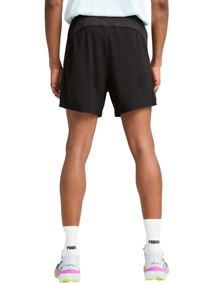 Hombre vistiendo shorts deportivos PUMA de color negro, diseñados para correr.