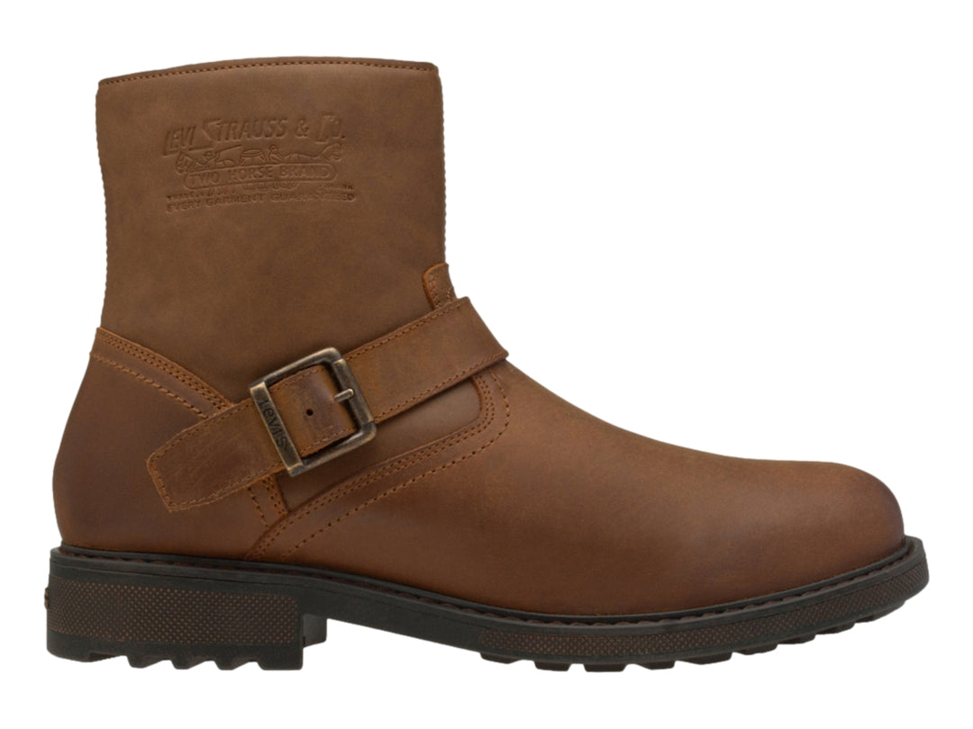 Bota casual color ocre para hombre con correa y hebilla metálica, suela marrón oscuro dentada.