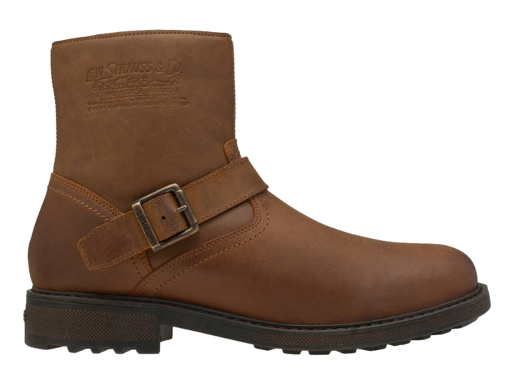 Bota casual color ocre para hombre con correa y hebilla metálica, suela marrón oscuro dentada.