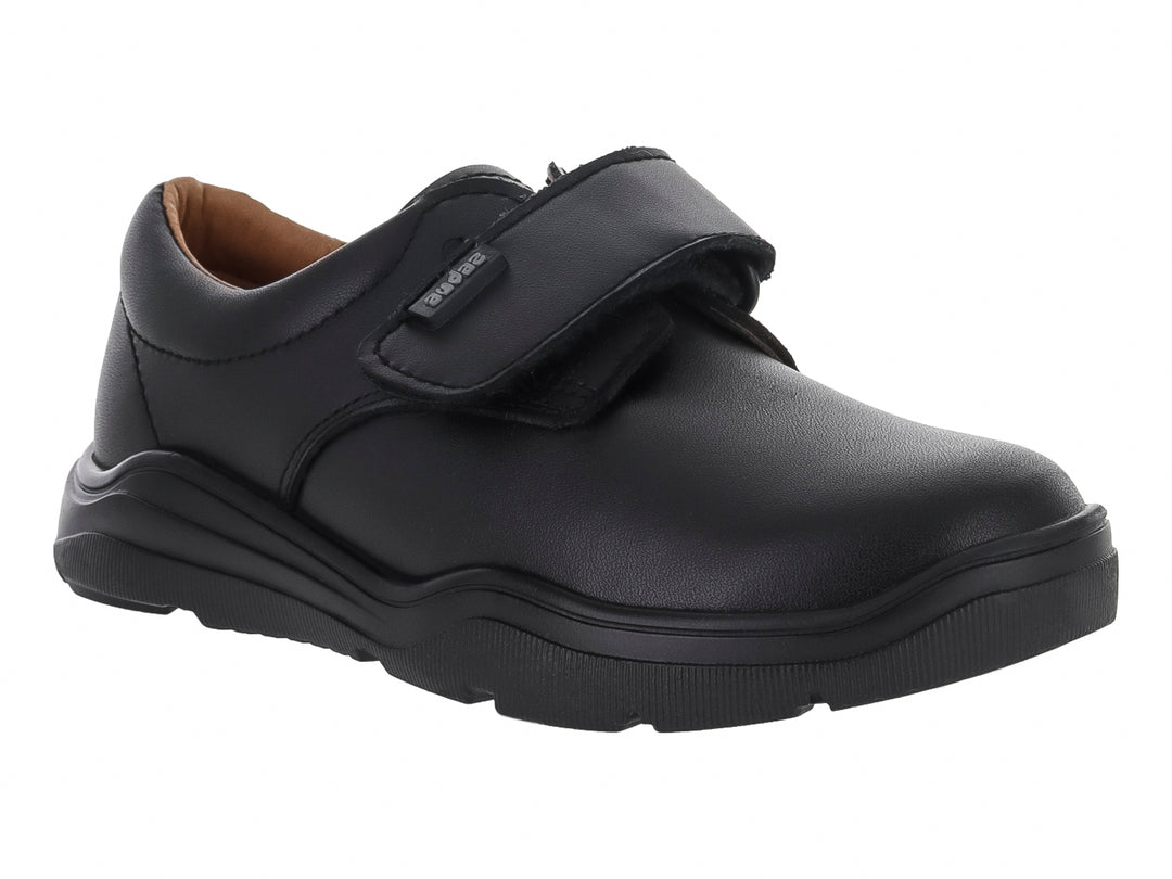 Zapato infantil color negro con cierre de velcro y suela gruesa.