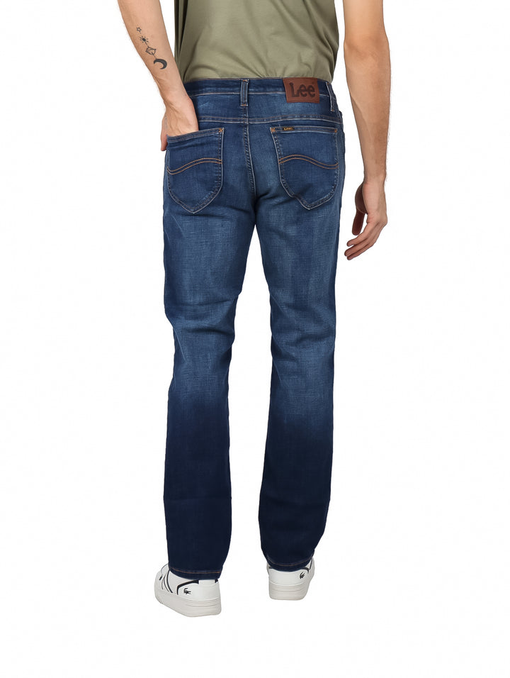 Hombre vistiendo pantalones LEE slim fit en color azul índigo con efecto lavado.