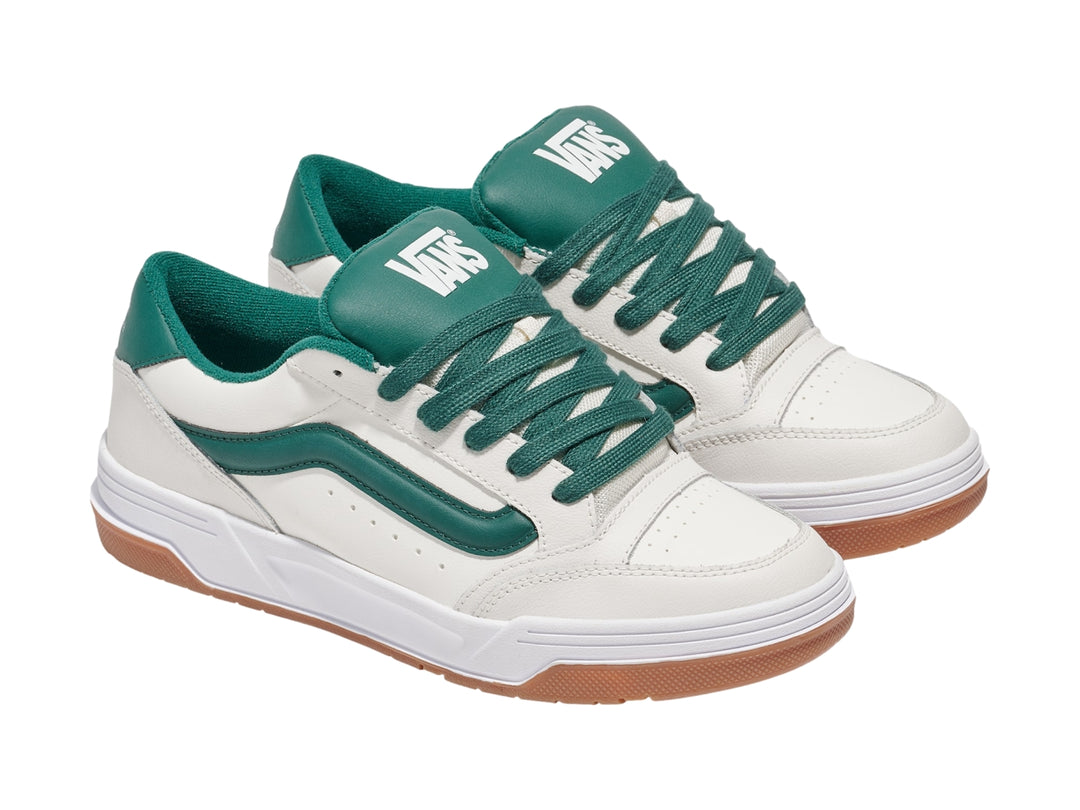Tenis Vans blancos con franja y cordones verdes y suela de goma color marrón.