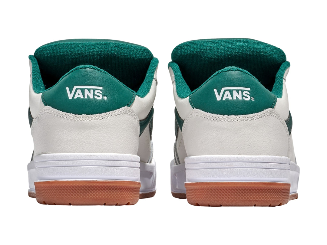 Tenis Vans blancos con franja y cordones verdes y suela de goma color marrón.
