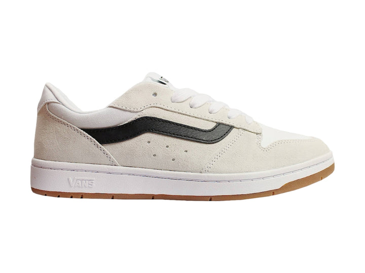 Tenis Vans blancos con franja lateral negra y suela de goma color miel.