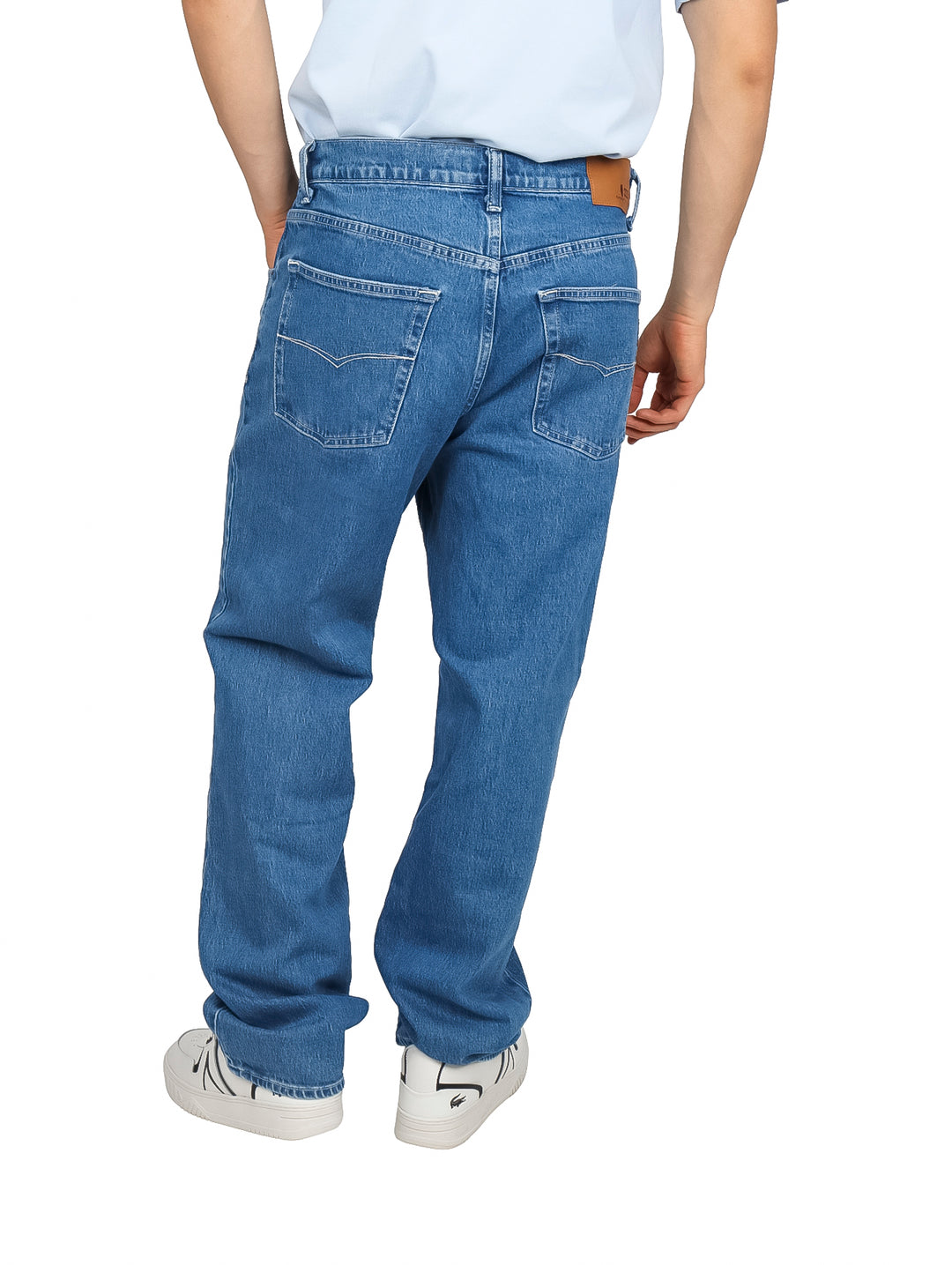 Hombre vistiendo pantalones jeans de color azul claro con tenis blancos.