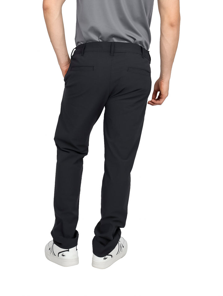 Hombre vistiendo pantalones negros de corte recto con tenis blancos y camiseta gris.