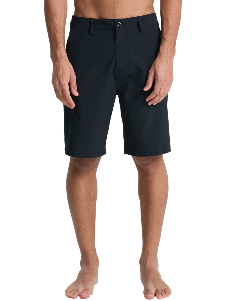 Hombre vistiendo shorts de surf color negro de la marca Quiksilver.