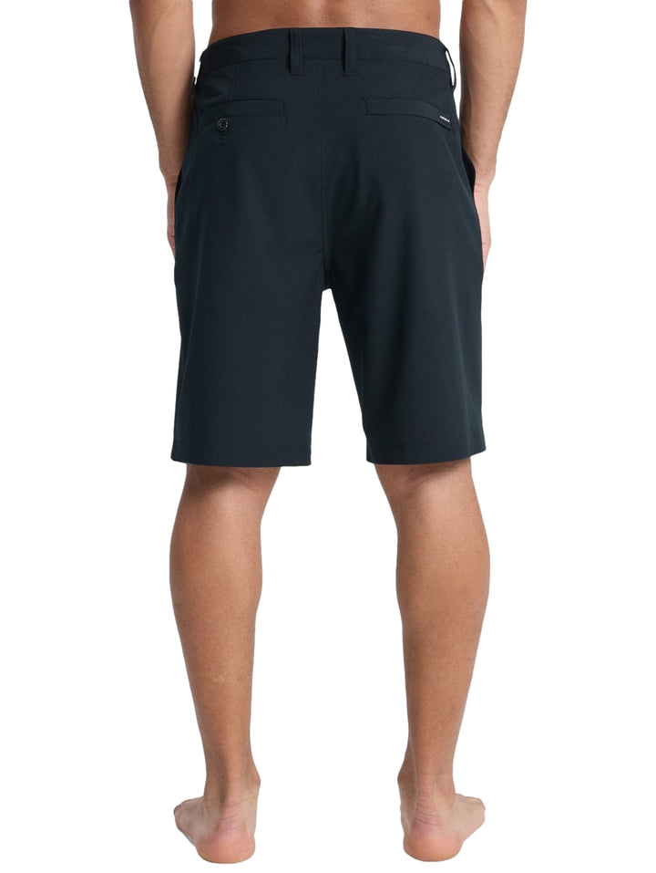 Hombre vistiendo shorts de surf color negro de la marca Quiksilver.