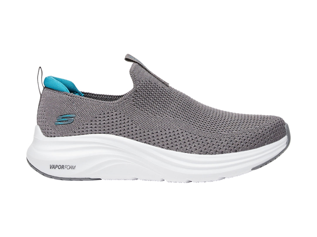 Zapato deportivo SKECHERS color gris con suela blanca y detalles en azul, estilo slip-on.