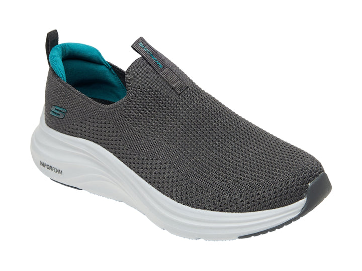 Zapato deportivo SKECHERS color gris con suela blanca y detalles en azul, estilo slip-on.