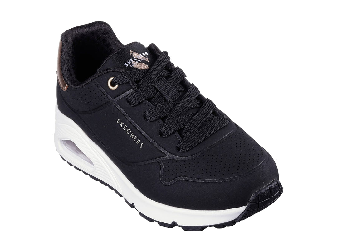 Tenis deportivos Skechers color negro con suela blanca y detalle metalizado en el talón.