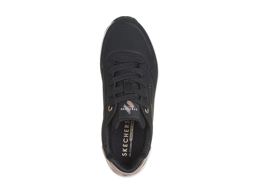 Tenis deportivos Skechers color negro con suela blanca y detalle metalizado en el talón.