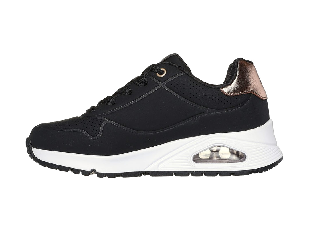 Tenis deportivos Skechers color negro con suela blanca y detalle metalizado en el talón.