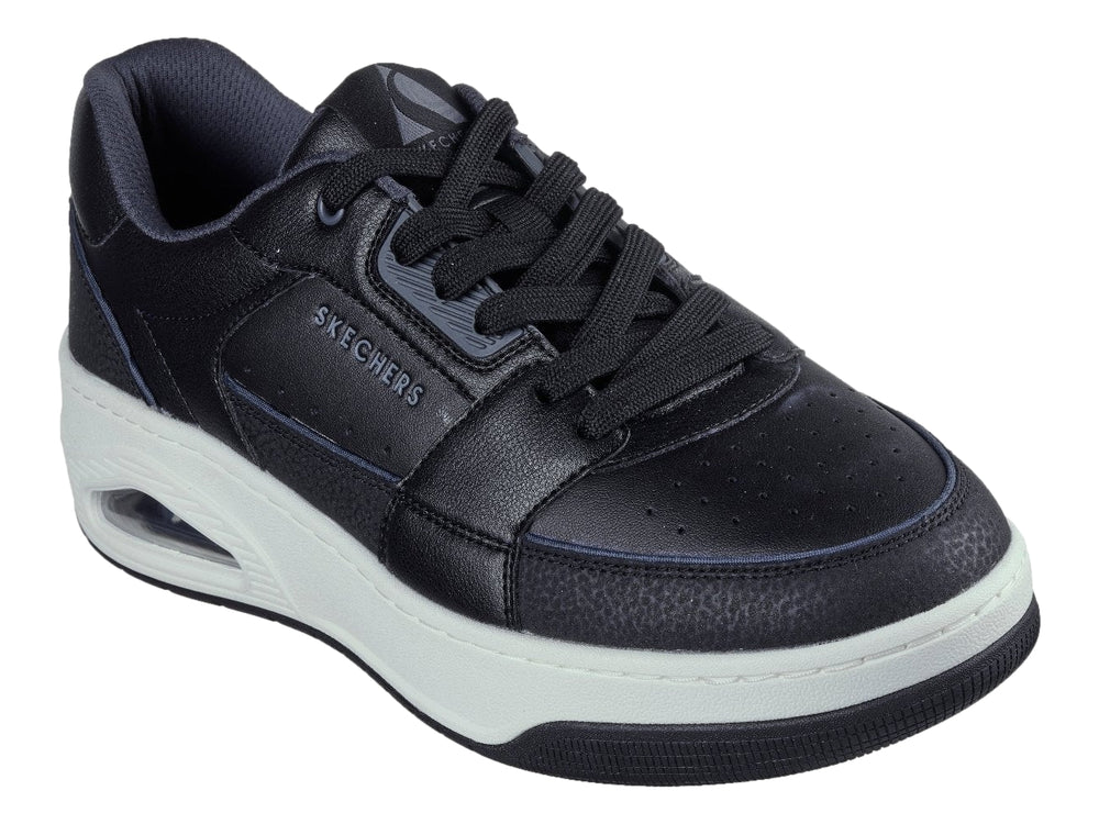 Tenis Skechers color negro con suela blanca gruesa y detalle en turquesa en el talón.