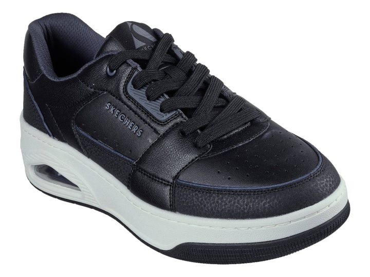 Tenis Skechers color negro con suela blanca gruesa y detalle en turquesa en el talón.