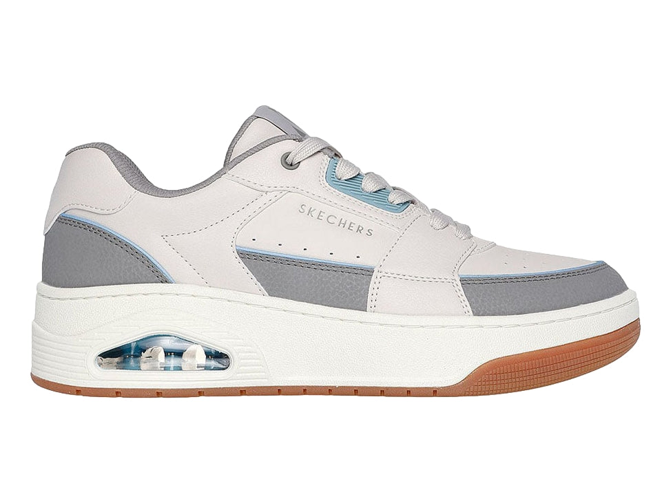 Tenis Skechers One Court color beige y gris con suela marrón y cámara de aire en el talón.